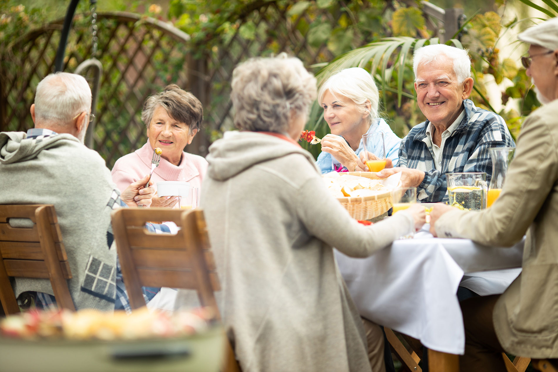 Ältere Menschen – hier eine gesellige Runde an einem Tisch im Freien – sollten Alkohol maßvoll genießen.