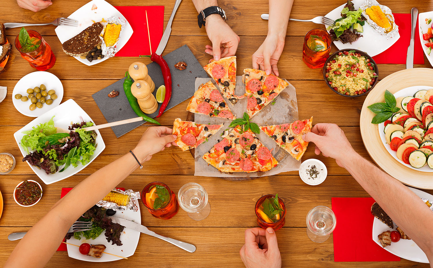 Gemeinsames Pizzaessen: Mahlzeiten vor und während des Trinkens verzögern die Wirkung des Alkohols.