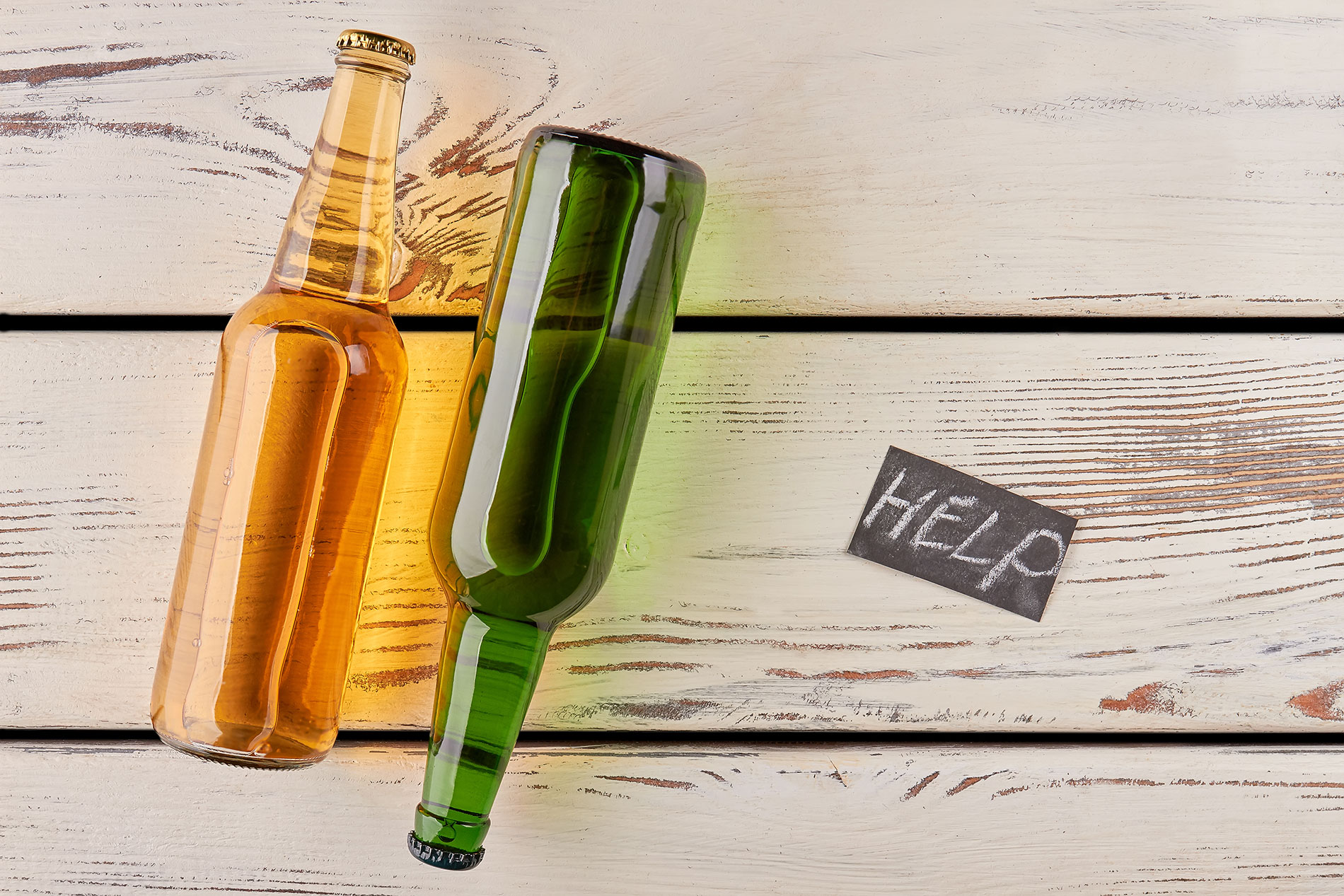 Alkoholflaschen und Schriftzug „Help“: In Österreich gibt es diverse Anlaufstellen bei Problemen mit Alkohol.